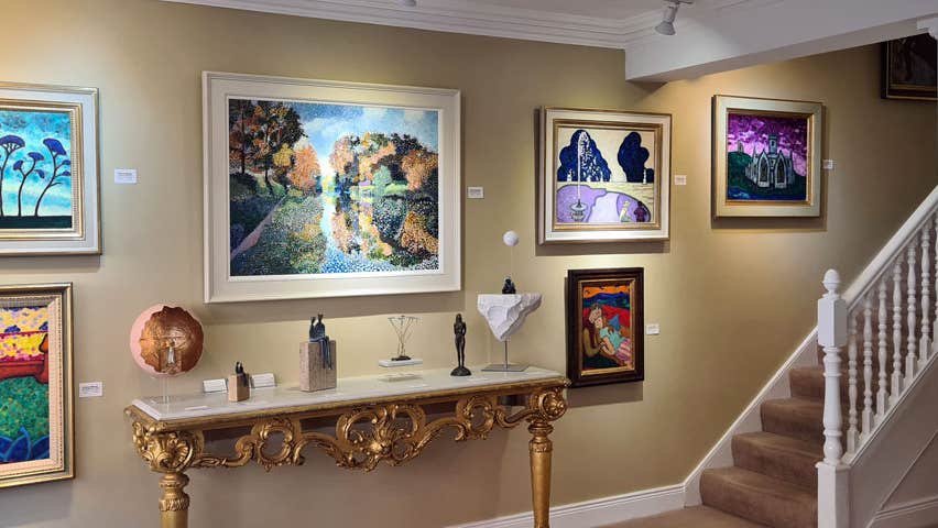 Image of six paintings on a wall and stairs on the right hand side