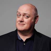 A man with quizzical smile in dark shirt and jacket.