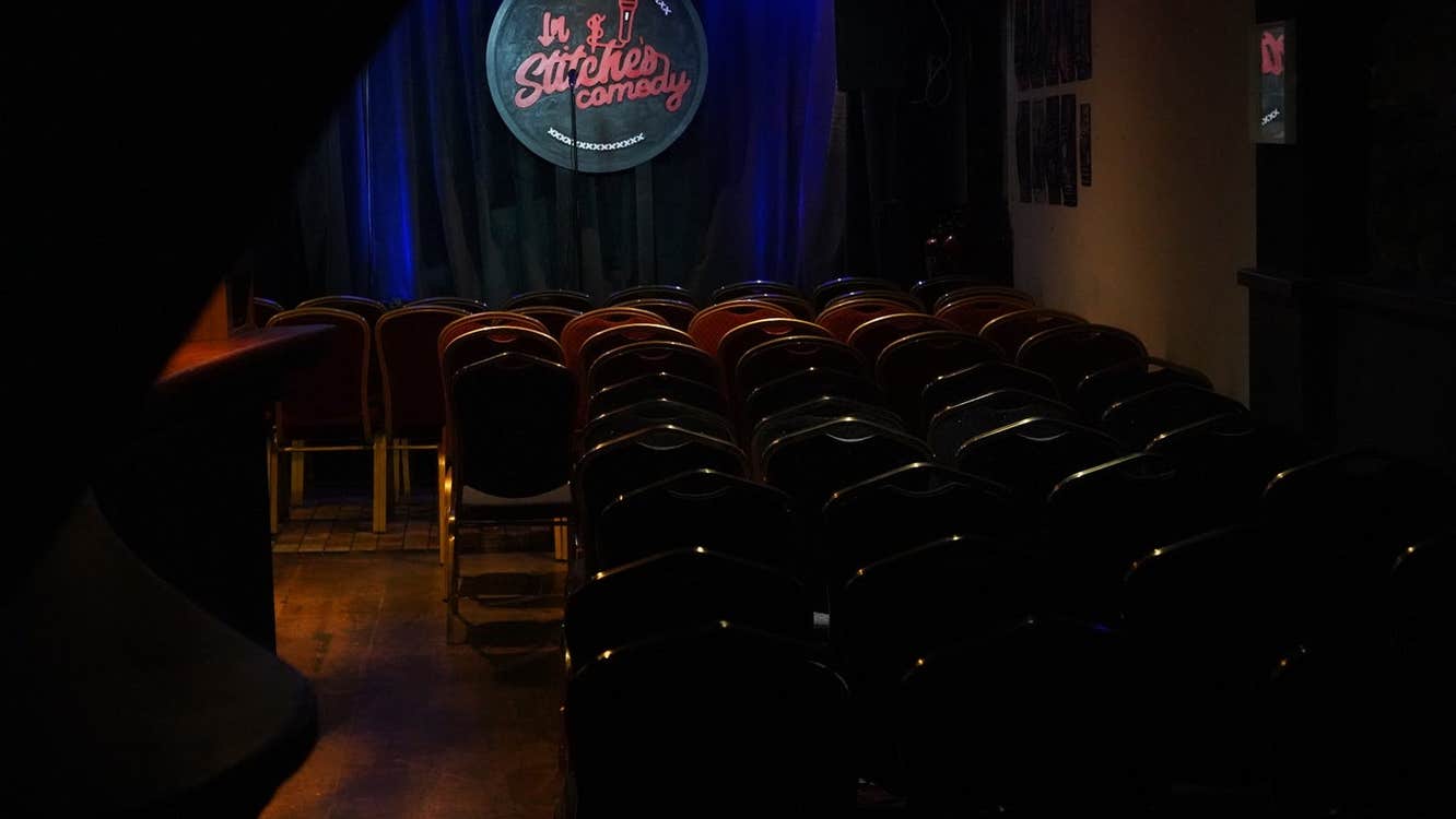 A dimly lit stage with a comedy club logo