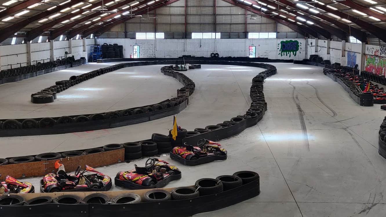 Indoor karting track with yellow and red go karts and path made by tyres