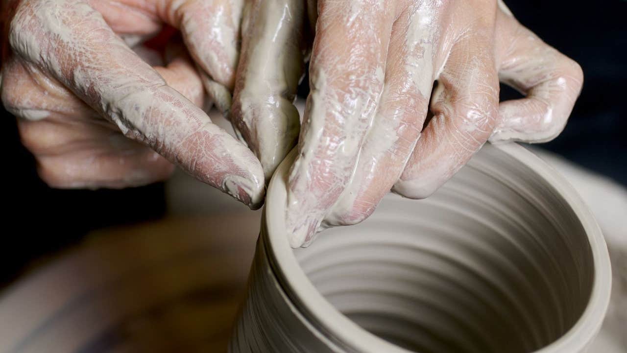 Hands shaping clay on a pottery wheel
