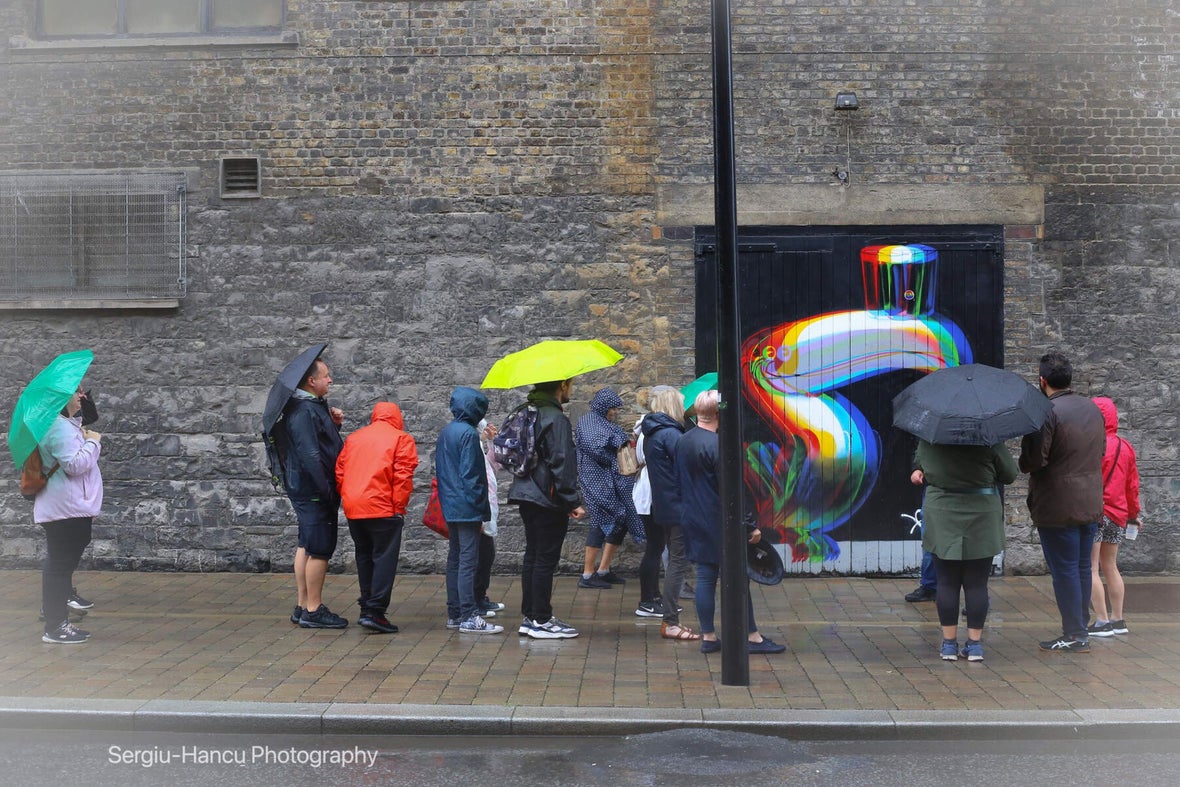 A walking tour looking at a piece of street art of a toucan with a Guinness beer on its beak.