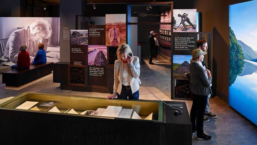 Visitors viewing artefacts in a display case and on AV screens at an exhibition