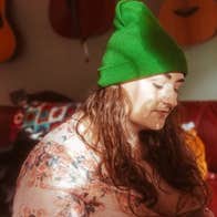 A woman in green wooly hat looking downwards.