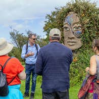 People and a tour guide in a field at a stone monument