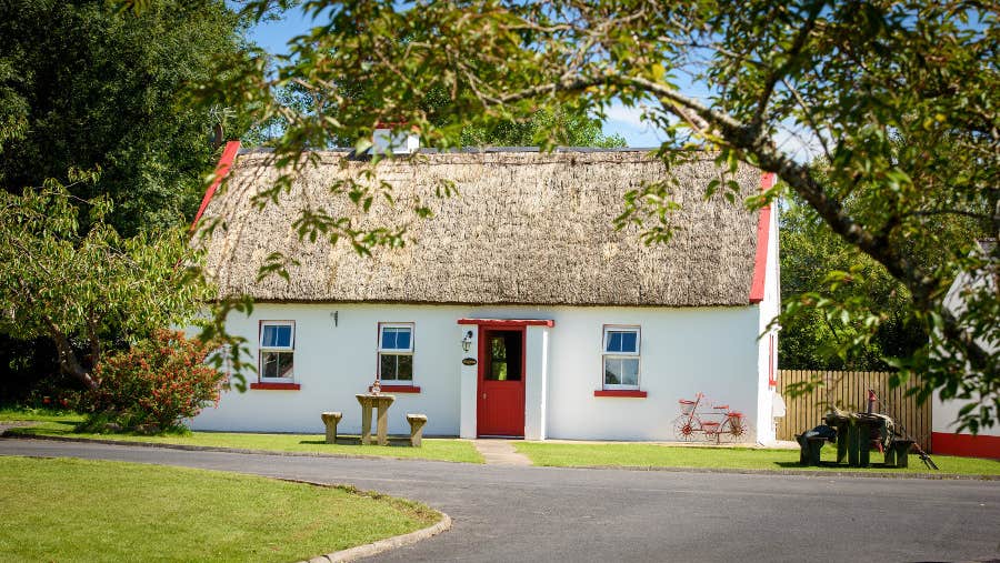 View of white cottage with red door