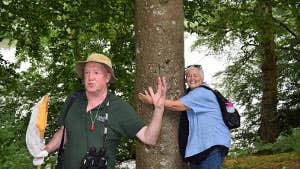 Image of tour guide with tour member hugging a tree
