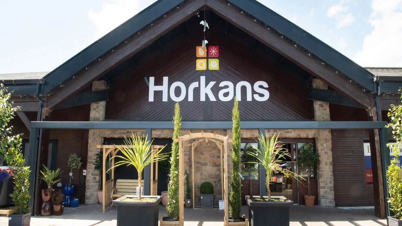 Front entrance of a business with wooden façade stone pillars and potted plants outside