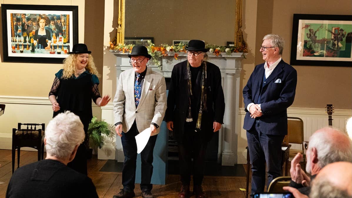 4 people standing in front of a fireplace performing to an audience