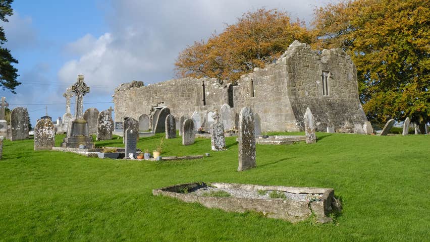 The ruins of a church with some ancient headstones scattered amongst green grass