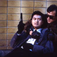 A man with a pistol is on the ground, being held from behind by another man.