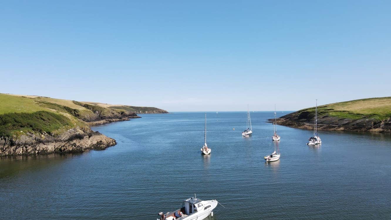 Boats sailing out for the harbour with green land either size