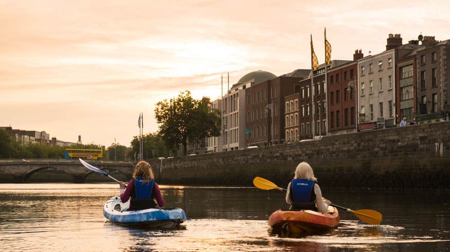 Two girls kayaking down the River Liffey in Dublin City at sunset