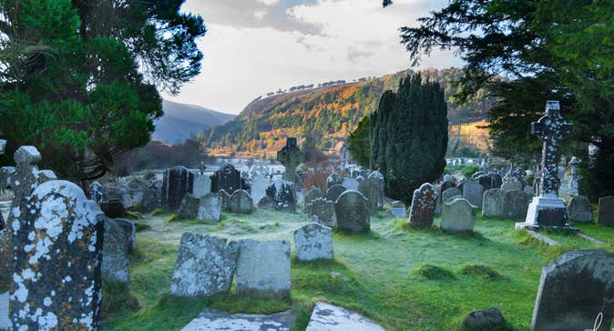 Ancient gravestones with overgrown grass in an old cemetery in Wicklow.