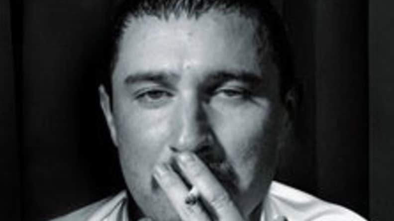 Comedian and actor Tom Rosenthal - headshot of man with half closed eyes and a cigarette up to his mouth