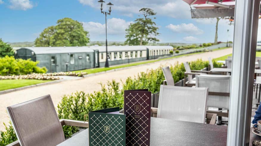 Dining tables and chairs in front of a railway carriage at Glenlo Abbey Hotel and Estate, Galway.