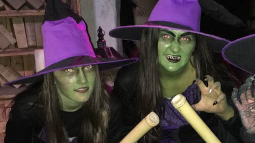 2 people dressed as witches in dark purple hats, green faces and black capes