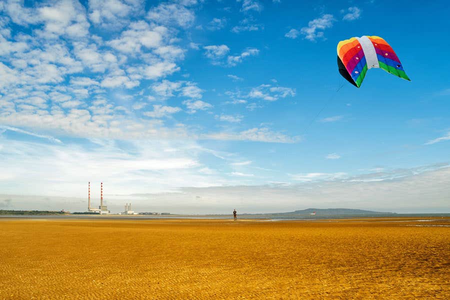A man flying a colourful kite on Sandymount Strand in Dublin