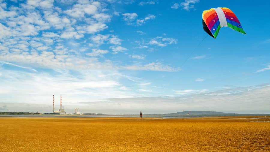 A man flying a colourful kite on Sandymount Strand in Dublin