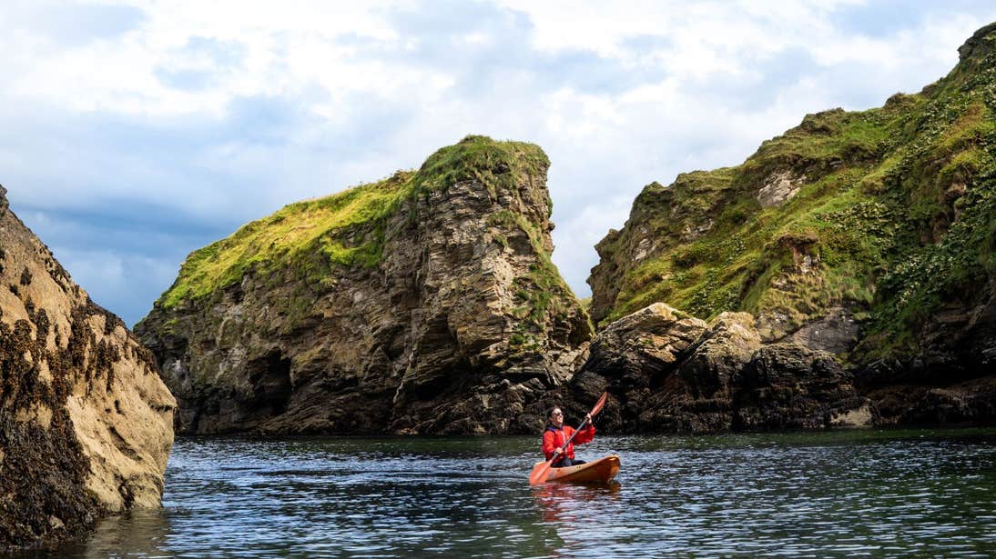 A person in a kayak with cliffs in the backdrop