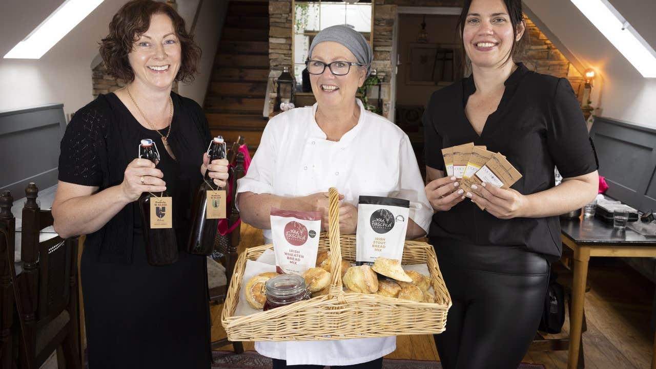 Three ladies standing side by side holding products they have made