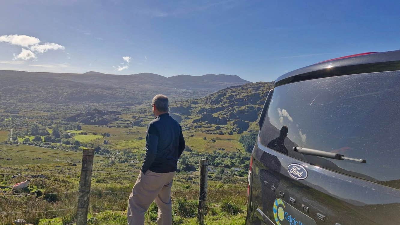 A man looking out over a green valley beside the Celtic Ways Ireland touring mini van