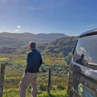 A man looking out over a green valley beside the Celtic Ways Ireland touring mini van