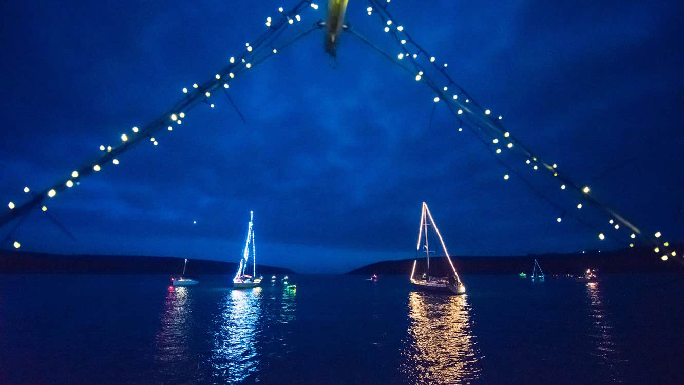 Kinsale St. Patrick's Maritime Parade, at night 2 sailing boats lit up with strings of lights