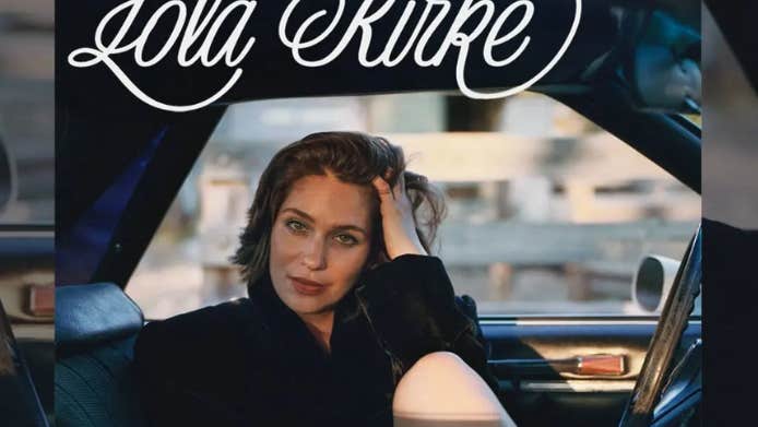 musician, actor and author Lola Kirke, a woman seated in a car, with her fingers from left hand in her hair.