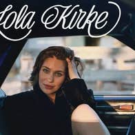 musician, actor and author Lola Kirke, a woman seated in a car, with her fingers from left hand in her hair.