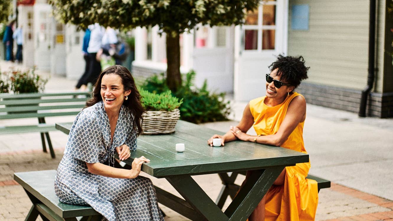 Two ladies smiling and enjoying an espresso outside at a café in Kildare Village