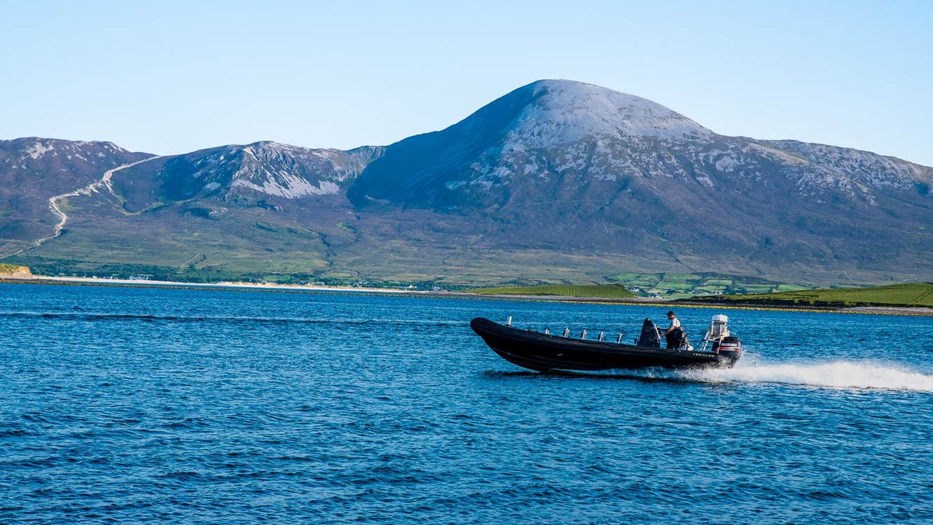 A small boat at sea with a mountain in the background