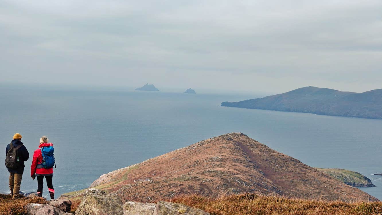 Two people taking a break while out hiking to look out at the sea view and Skellig Rock