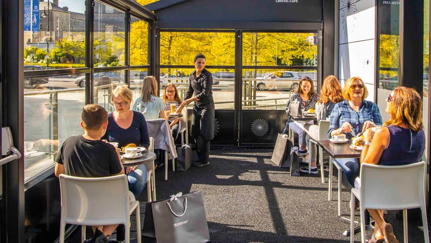 People sitting in a cafe as the sun comes through large glass windows