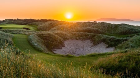Sunset over golf course bunker with grass to the forefront