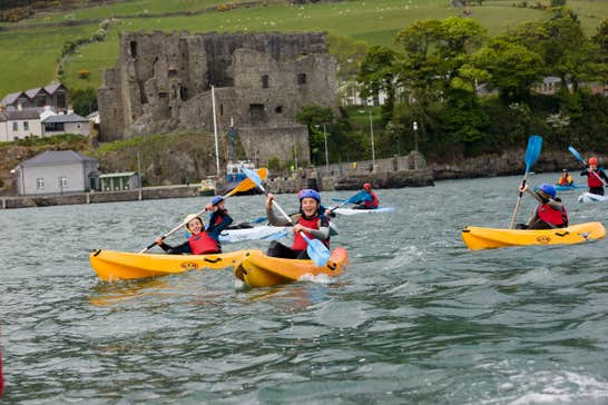 Kids kayaking in yellow kayaks in front of a castle in Louth