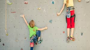 Two children with colourful clothes on a climbing wall