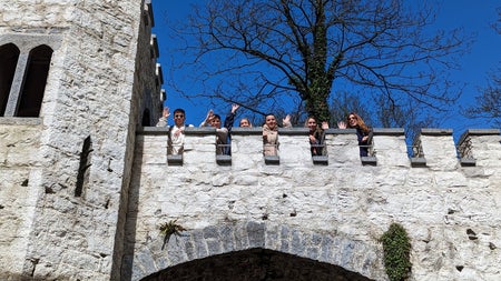 A tour group looking down over a castle wall to the camera below
