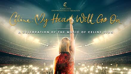 Rear view of woman in red dress with right arm straight up in the air looking out over an audience