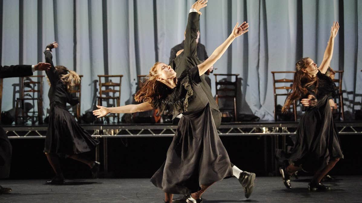 MÁM, Teac Damsa, O'Reilly Theatre, DTF 2019. People in long, dark clothes are dancing on a stage with arms outstretched.