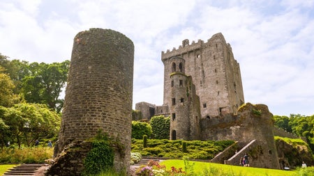 The ruins of a castle and a tower with people walking around the ruins