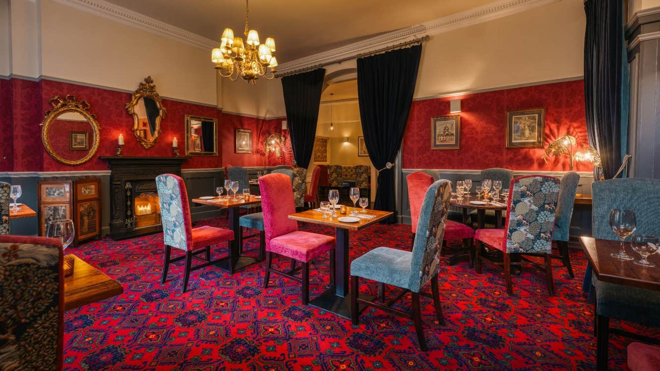 Elegant restaurant dining room with Georgian décor ornate mirrors patterned carpet and warmly lit tables
