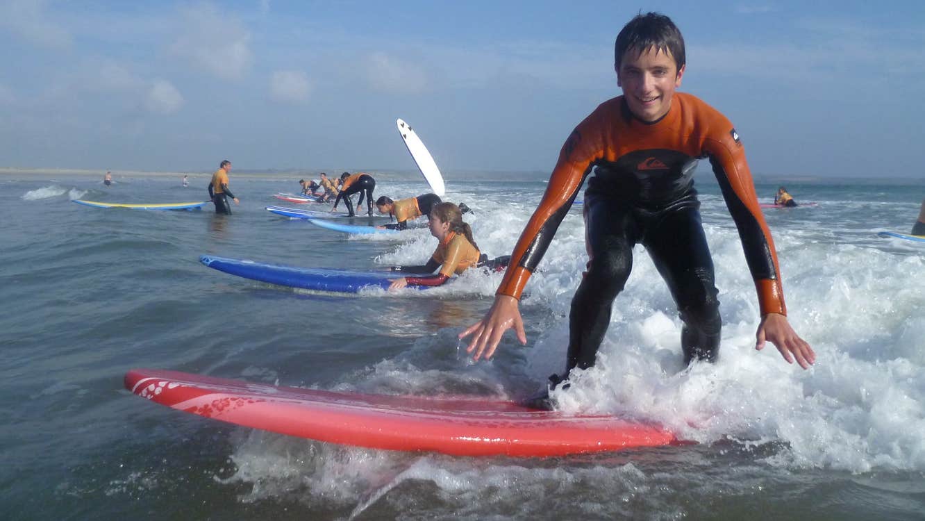 A boy on his surf board during a surf lesson in the sea with Freedom Surf School