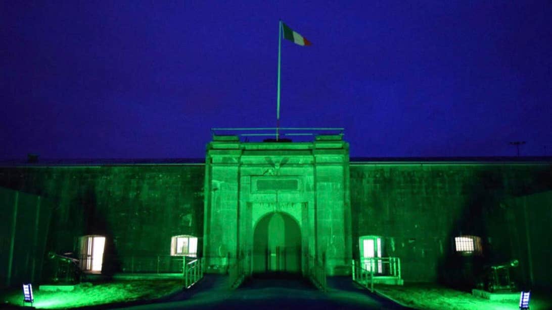 Exterior facade entrance to Spike Island lit up in green at night.