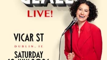 A laughing woman in red jacket holding a mic on a stand