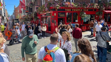 People gather in the sunshine on the street outside the Temple Bar pub in Dublin