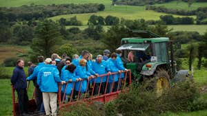 A tour group standing on trailer with a tractor as they enjoy a West Cork Farm Tour.