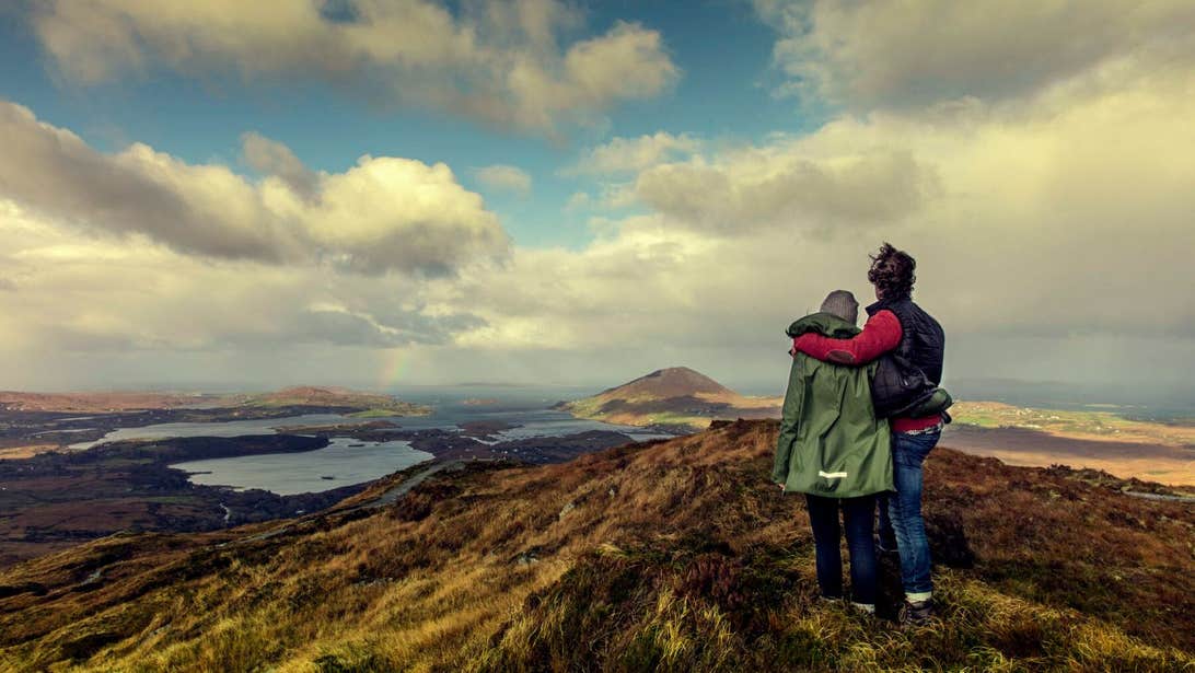 Two hikers on Diamond Hill overlooking Connemara in an embrace.