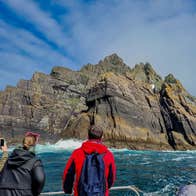 Three people on a boat taking photos of the Skellig Islands