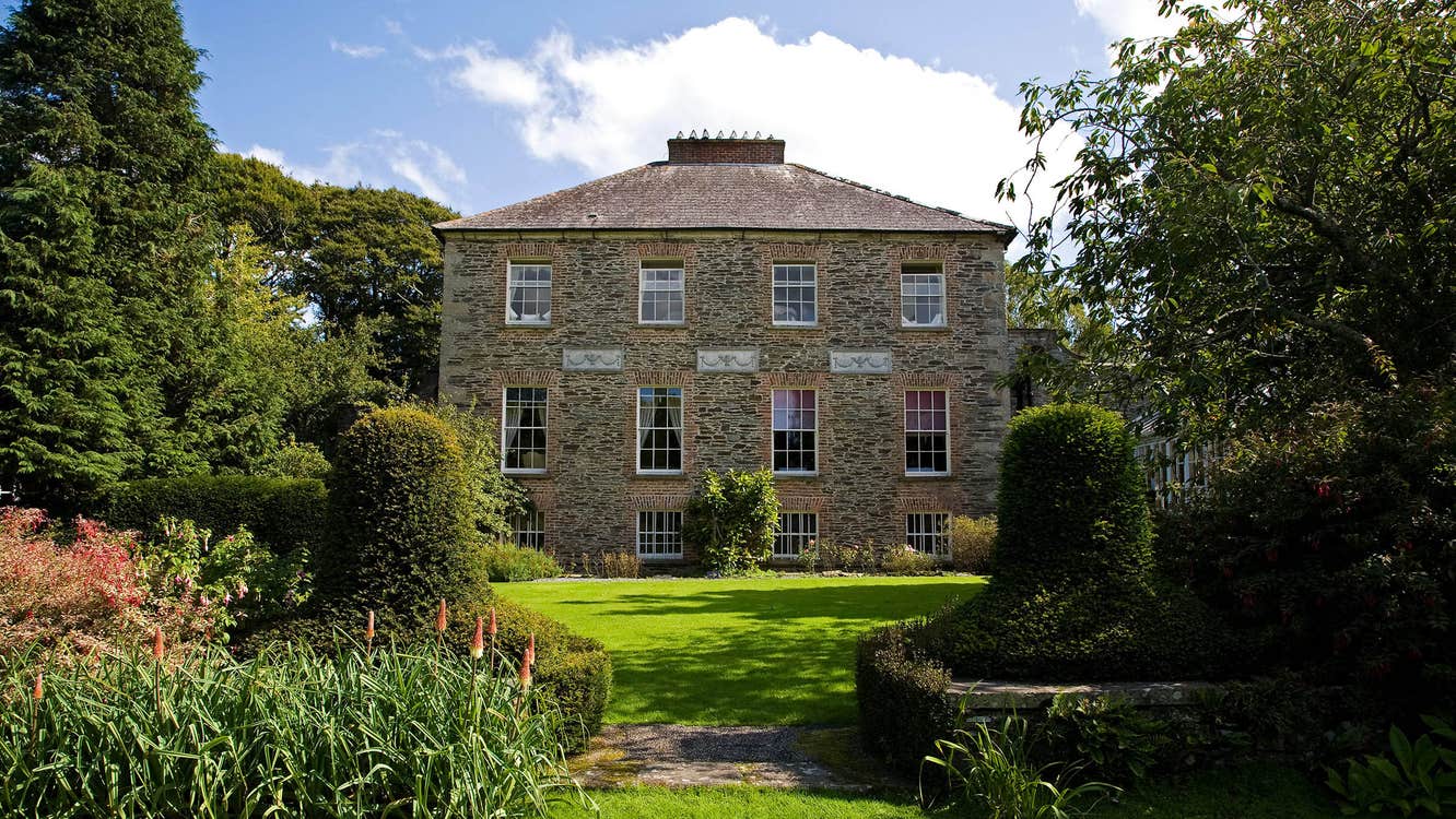 The exterior of a house at Kilmokea Country Manor Gardens with trees on either side.